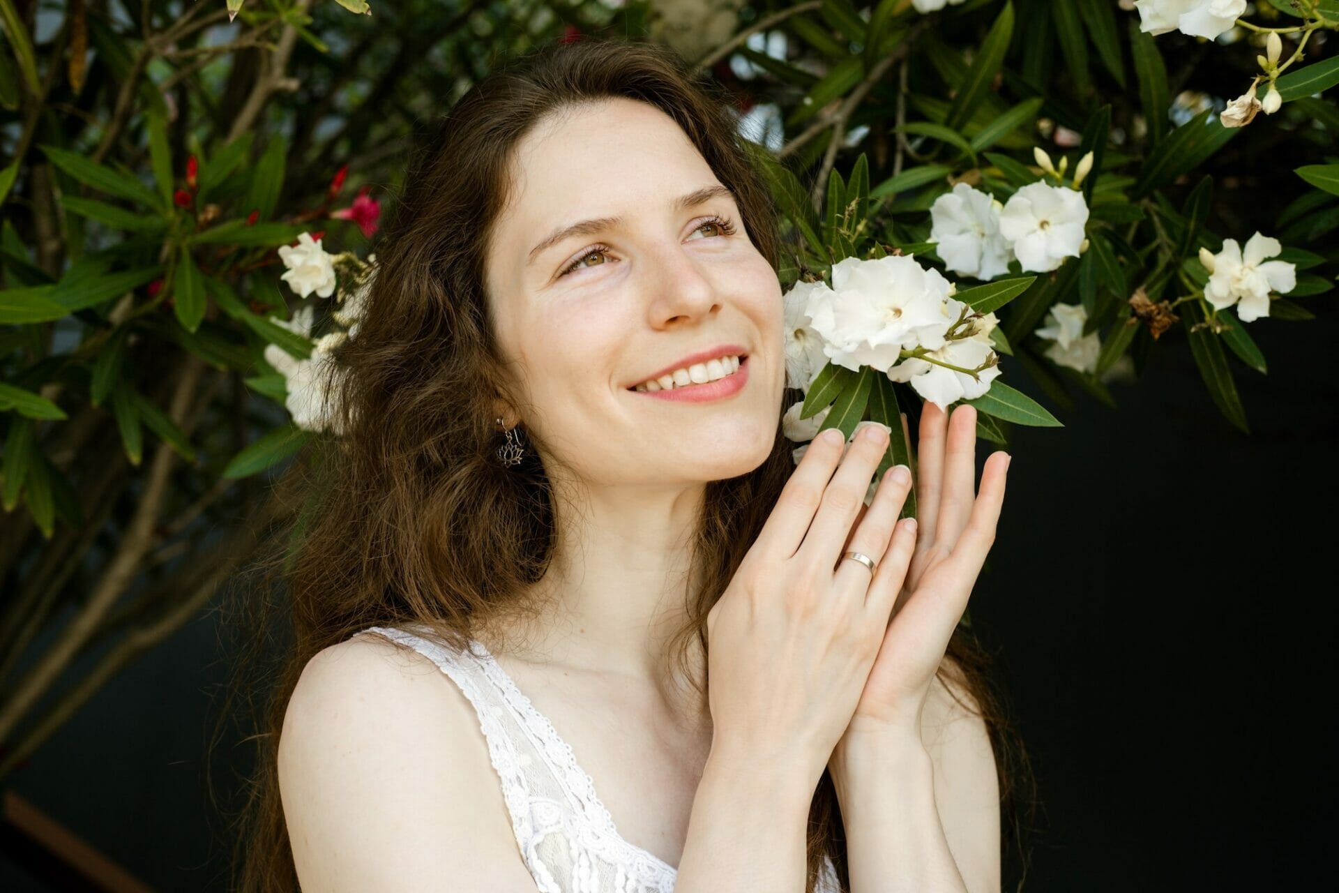 Close up female portrait of young woman with healthy tooth and glowing skin with blooming tree.