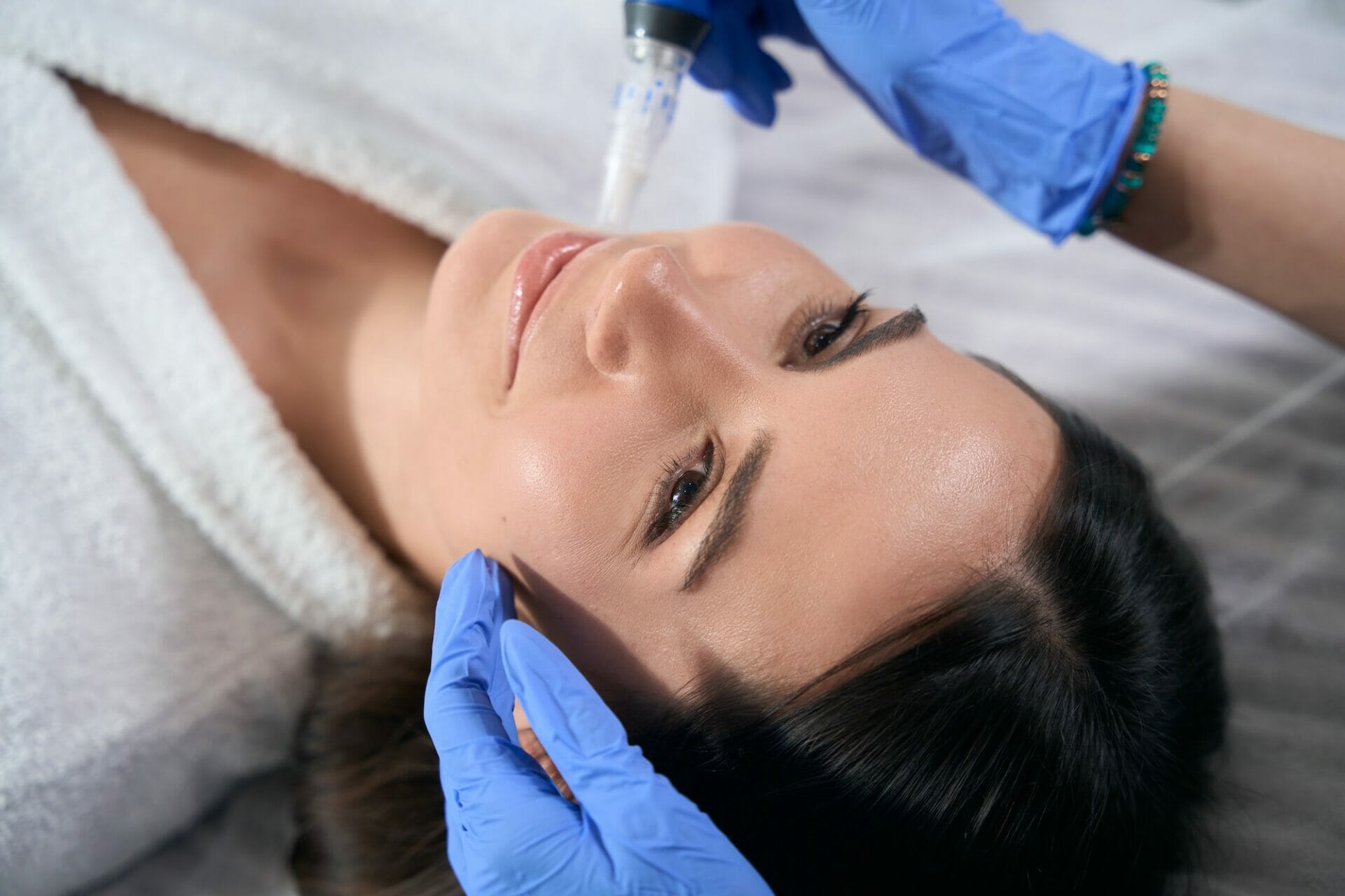 Cosmetologist holds automatic pen in microneedle mesotherapy and doing procedure