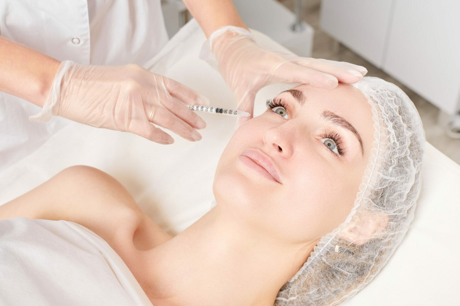 Cosmetologist makes rejuvenation injection in woman face, anti aging procedure in beauty salon