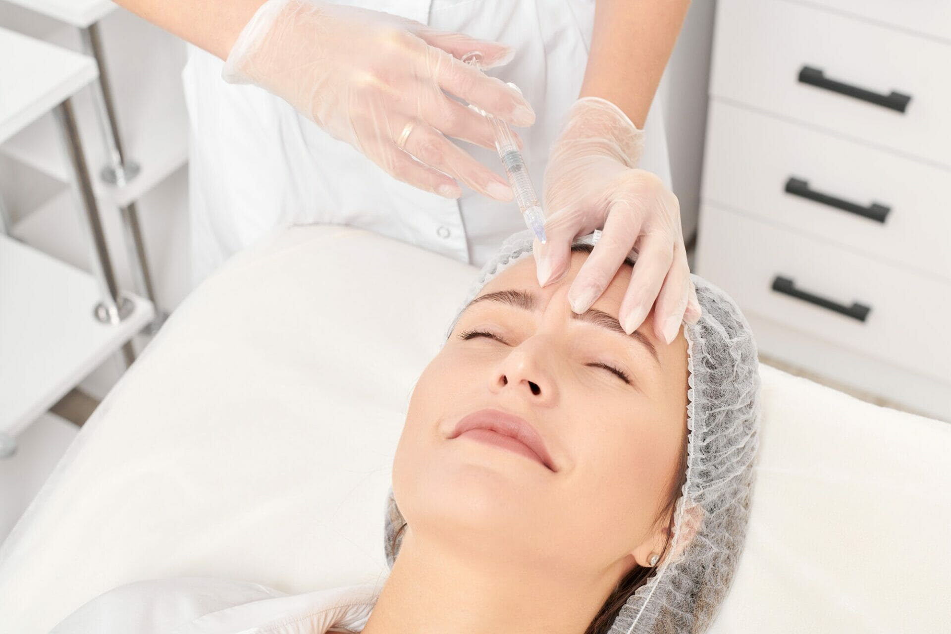 Cosmetologist makes rejuvenation injection in woman face, anti aging procedure in beauty salon